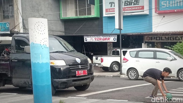 Seorang anak mengambil bola di tengah jalan.