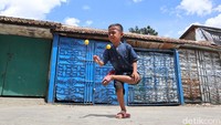 Seorang bocah sedang menunjukkan aksinya bermain lato-lato dengan gaya satu kakinya yang ditekuk. (Foto: Bima Bagaskara/detikJabar)