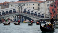 Pria berpakaian sebagai La Befana, seorang wanita tua imajiner yang dianggap membawa hadiah untuk anak-anak mendayung perahu menyusuri Grand Canal di Venesia, Italia, Jumat (6/1/2023). 