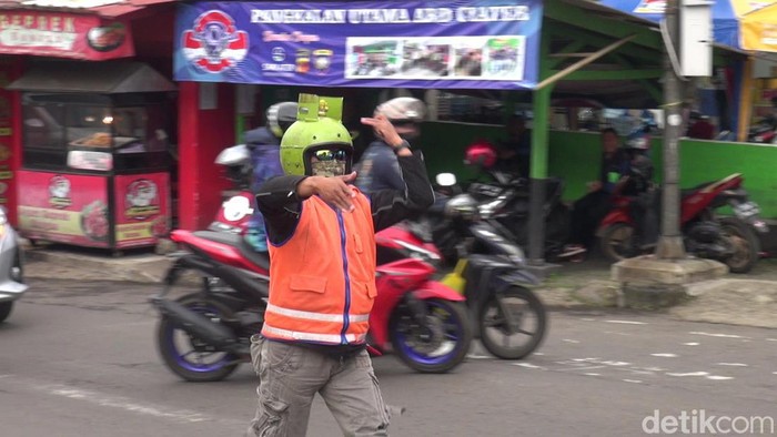 Eman (43) jukir unik pakai helm gas melon di Ciater, Subang.