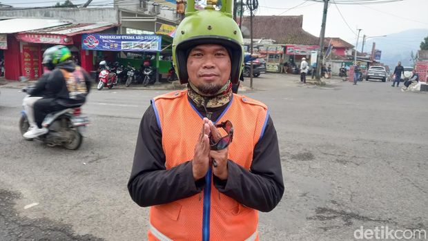Eman (43) jukir unik pakai helm gas melon di Ciater, Subang.