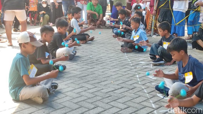 Lomba lato-lato digelar di Sidoarjo, Minggu (8/1/2023). Di babak semifinal, peserta harus memainkan lato-lato sambil duduk, jongkok serta berjalan memutar.