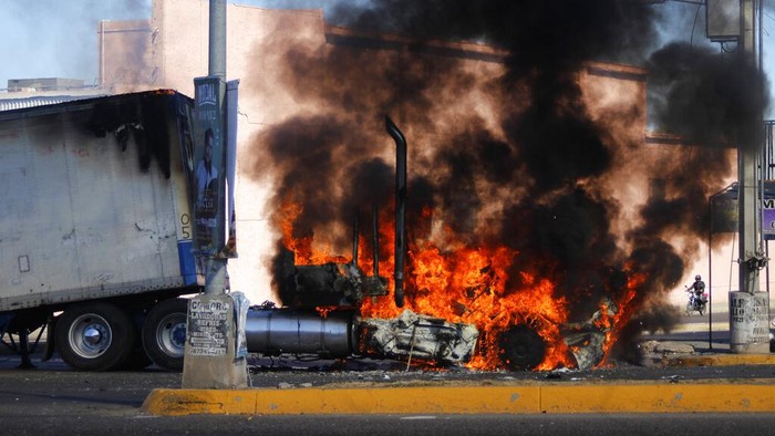 Army soldiers drive past a destroyed vehicle on the streets of Jesus Maria, Mexico, on Saturday, Jan. 7, 2023, the small town where Ovidio Guzman was detained earlier in the week. Thursdays government operation to detain Ovidio, the son of imprisoned drug lord Joaquin 