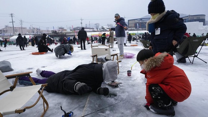 Melihat Keseruan Mancing Ikan di Sungai Beku Korea Selatan Participants cast lines through holes drilled in the surface of a frozen river during a trout catching contest in Hwacheon, South Korea, Saturday, Jan. 7, 2023. The contest is part of an annual ice festival which draws over one million visitors every year. (AP Photo/Ahn Young-joon)