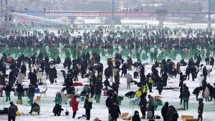 Participants cast lines through holes drilled in the surface of a frozen river during a trout catching contest in Hwacheon, South Korea, Saturday, Jan. 7, 2023. The contest is part of an annual ice festival which draws over one million visitors every year. (AP Photo/Ahn Young-joon)