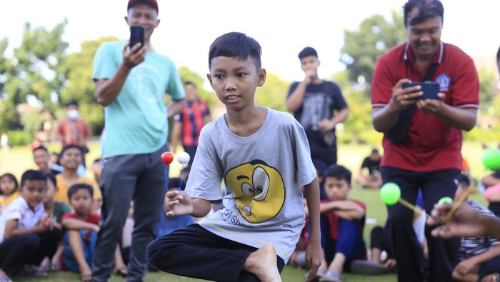 Peserta lomba lato-lato di Klungkung, Bali, unjuk kebolehan dengan menekuk kaki sembari main lato-lato.
