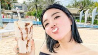Ketika berlibur ke pantai sekalipun, ia tak pernah lupa memesan minuman. Kali ini ia memilih milkshake yang manis untuk menyegarkan tubuhnya. Foto: Instagram/wikasalim