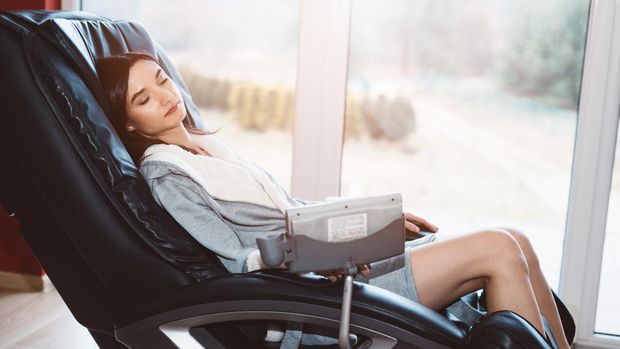Young woman relaxing on the massaging chair at home