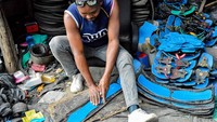 Seorang perajin menyelesaikan pembuatan sandal dari ban bekas di bengkel jalanan kota Nakuru. 
