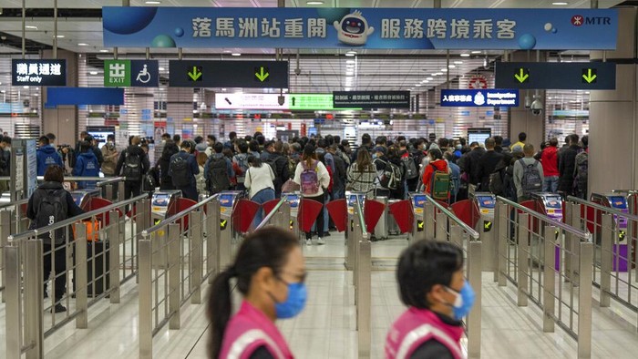 Beijing Ambil Tindakan Balasan Negara yang Batasi Pendatang dari China Workers wearing face masks walk by as travelers wait at the departure hall of the Lok Ma Chau station following the reopening of crossing border with mainland China, in Hong Kong, Sunday, Jan. 8, 2023. Travelers crossing between Hong Kong and mainland China, however, are still required to show a negative COVID-19 test taken within the last 48 hours, a measure China has protested when imposed by other countries. (AP Photo/Bertha Wang)