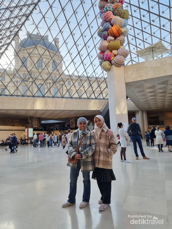 Berpose sejenak di dalam piramida kaca Louvre yang terkenal.