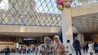 Berpose sejenak di dalam piramida kaca Louvre yang terkenal.