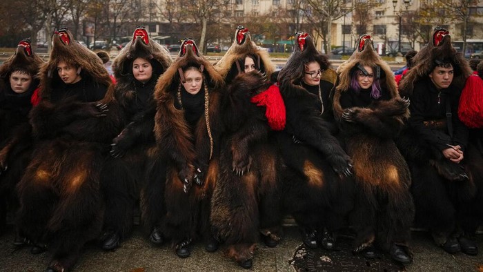 Ritual Mengusir Roh Jahat Jadi Daya Tarik Wisata di Rumania Youths wearing bear fur costumes pause during a parade showcasing winter traditions from the northeast of the country in Bucharest, Romania, Sunday, Dec. 18, 2022. Centuries ago, people in what is now northeast Romania would don bear fur and dance to fend off evil spirits. Nowadays, the custom lives on as a popular festival that has been drawing crowds of tourists. The so-called 'dancing bears festival' takes place every December, starting in the days before Christmas and ending with the New Year's Eve. (AP Photo/Andreea Alexandru)