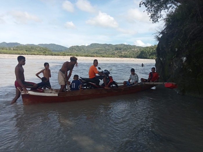 Warga Amfoang, Kupang, NTT, terpaksa menggunakan jasa tukang pikul hingga menaikkan sepeda motor ke atas perahu agar bisa menerobos banjir.