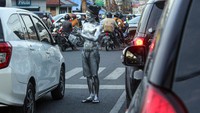 Pengamen manusia silver beraksi di persimpangan Jalan Yos Sudarso, Kota Medan, Sumatera Utara, Senin (9/1/2023).