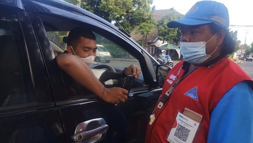 Salah satu pengunjung di Lapangan Puputan Badung tampak men-scan barcode pada rompi petugas parkir, Minggu (31/7/2022).