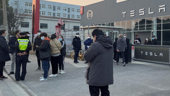 Penampakan Showroom Tesla Digeruduk Konsumen Gegara Diskon People walk out from a building as police officer stands near the entrance, after demonstrating at the Tesla delivery centre in Shanghai, China January 7, 2023. REUTERS/Brenda Goh