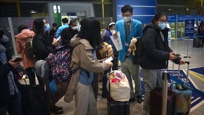 Potret Kedatangan Pelancong Pertama Setelah China Cabut Karantina Workers help travelers fill out an electronic declaration of their COVID-19 health status in the international arrivals area at Beijing Capital International Airport in Beijing, Monday, Jan. 9, 2023. The first international travelers are arriving in China without the mandatory quarantine that had been imposed at the start of the pandemic three years ago after restrictions were lifted beginning on Sunday. (AP Photo/Mark Schiefelbein)