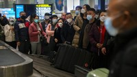 Pelancong yang memakai masker wajah menunggu barang bawaan mereka di area kedatangan internasional di Bandara Internasional Ibukota Beijing di Beijing, Senin (9/1/2023).  