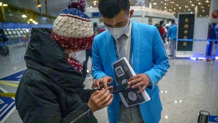Potret Kedatangan Pelancong Pertama Setelah China Cabut Karantina Workers help travelers fill out an electronic declaration of their COVID-19 health status in the international arrivals area at Beijing Capital International Airport in Beijing, Monday, Jan. 9, 2023. The first international travelers are arriving in China without the mandatory quarantine that had been imposed at the start of the pandemic three years ago after restrictions were lifted beginning on Sunday. (AP Photo/Mark Schiefelbein)
