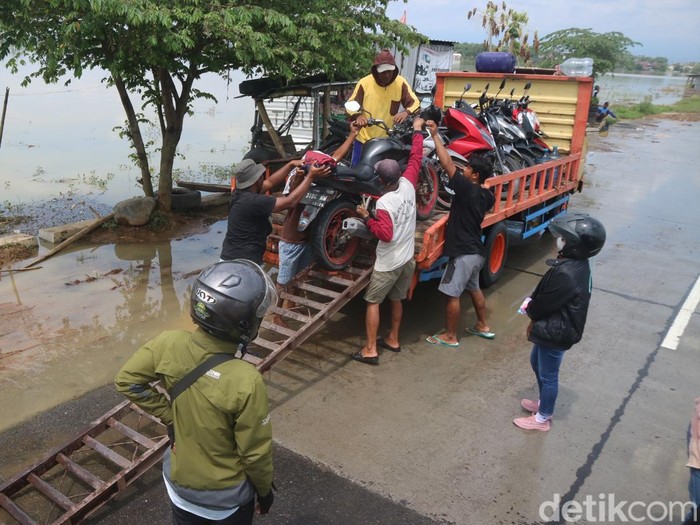 Sejumlah sepeda motor dinaikkan ke atas truk untuk menyeberangi banjir yang merendam jalan alternatif Pati-Rembang di Desa Tondomulyo, Kecamatan Jakenan, Pati, Selasa (10/1/2023).