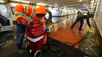 Para kru bekerja mengeringkan air hujan yang membanjiri jalur pejalan kaki Union Station, yang mengarah ke peron kereta api di Los Angeles. AP/Damian Dovarganes  