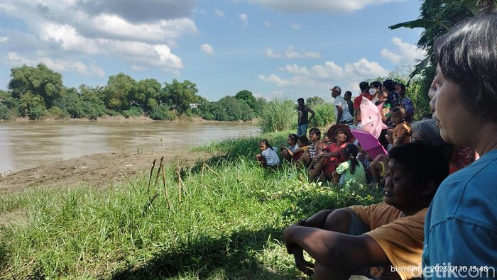 Keluarga dan tetangga menunggu di tepi sungai melihat proses pencarian anak