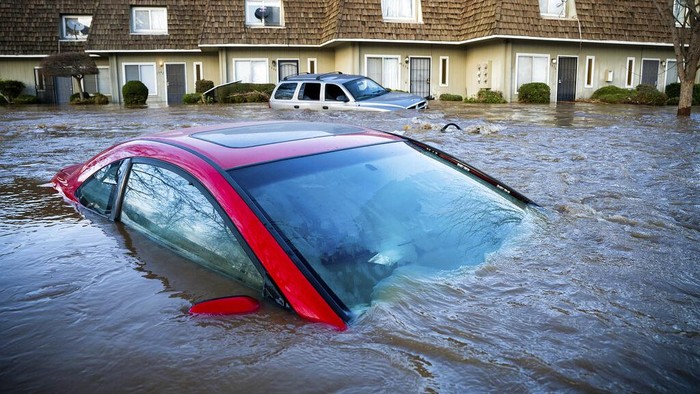 Mobil-mobil Jadi Korban Dahsyatnya Badai yang Menerjang California Floodwaters course through a neighborhood in Merced, Calif., on Tuesday, Jan. 10, 2023. Following days of rain, Bear Creek overflowed its banks leaving dozens of homes and vehicles surrounded by floodwaters. (AP Photo/Noah Berger)