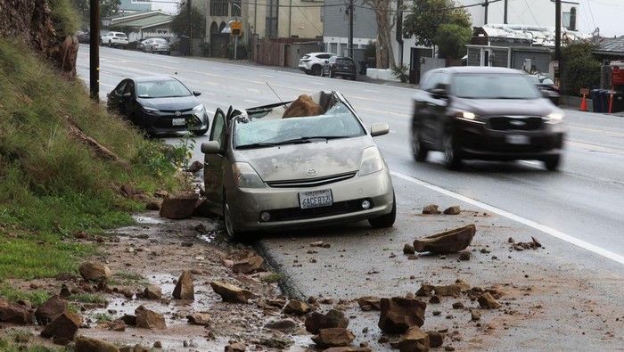 Ngeri! Gegara Badai Batu-batu Ini Jatuh Timpa Mobil CalTrans workers chip away at a huge boulder that fell on Malibu Canyon Road in Malibu, California, U.S., January 10, 2023. REUTERS/David Swanson