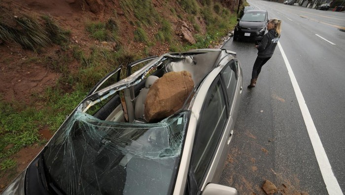 Ngeri! Gegara Badai Batu-batu Ini Jatuh Timpa Mobil CalTrans workers chip away at a huge boulder that fell on Malibu Canyon Road in Malibu, California, U.S., January 10, 2023. REUTERS/David Swanson