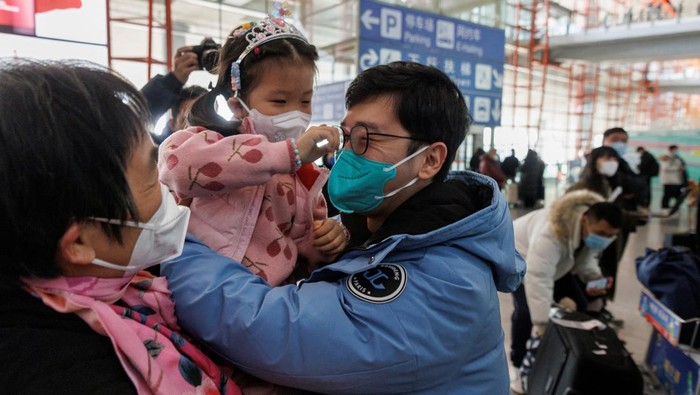 Reuni yang Telah Lama Dinanti Saat China Buka Kembali Perbasatan People embrace at the international arrivals gate at Beijing Capital International Airport after China lifted the coronavirus disease (COVID-19) quarantine requirement for inbound travellers in Beijing, China January 8, 2023. REUTERS/Thomas Peter