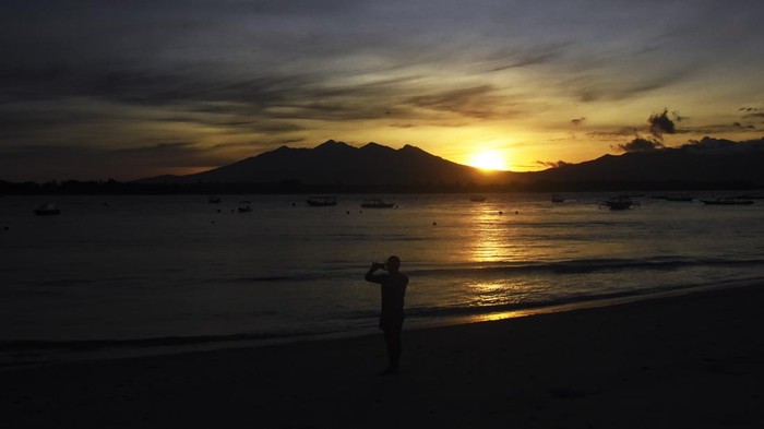 SUNRISE DI GILI TRAWANGAN Siluet Gunung Rinjani terlihat saat matahari terbit (sunrise) di pantai Gili Trawangan, Desa Gili Indah, Kecamatan Pemenang, Tanjung, Lombok Utara, NTB, Rabu (11/1/2023). Gili Trawangan merupakan satu dari tiga pulau kawasan wisata Gili Tramena (Gili Trawangan, Gili Meno, Gili Air) yang saat ini mulai ramai dikunjungi kembali oleh wisatawan mancanegara setelah sepi akibat pandemi COVID-19. ANTARA FOTO/Ahmad Subaidi/aww.
