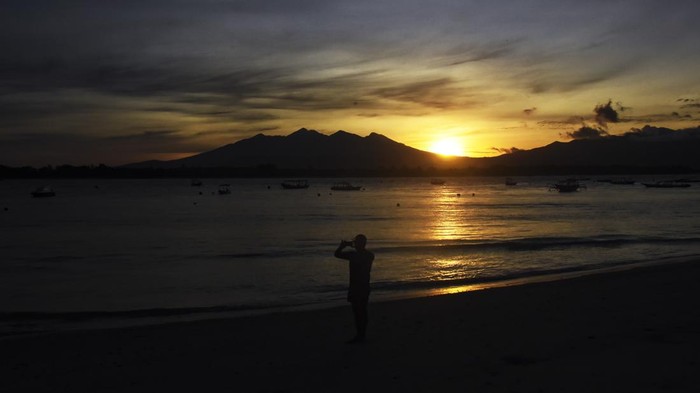 Siluet Gunung Rinjani terlihat saat matahari terbit (sunrise) di pantai Gili Trawangan, Desa Gili Indah, Kecamatan Pemenang, Tanjung, Lombok Utara, NTB, Rabu (11/1/2023). Gili Trawangan merupakan satu dari tiga pulau kawasan wisata Gili Tramena (Gili Trawangan, Gili Meno, Gili Air) yang saat ini mulai ramai dikunjungi kembali oleh wisatawan mancanegara setelah sepi akibat pandemi COVID-19. ANTARA FOTO/Ahmad Subaidi/aww.