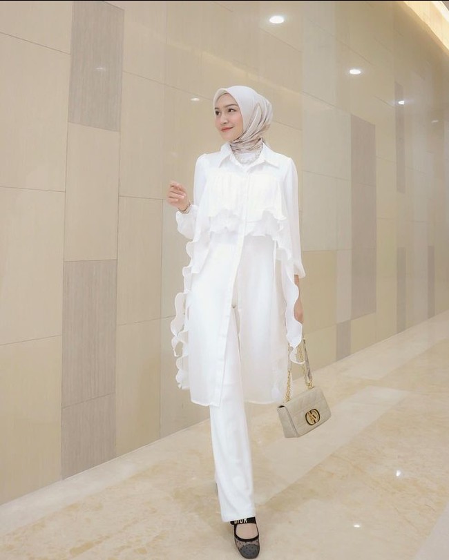 Melody juga mencoba gaya hijab pashmina dan segi empat untuk berbagai kegiatan. Item fashion favorit ala Melody Prima adalah midi dress, basic pants, blazer, vest, dan blouse motif. Seperi dalam foto ini, Melody terlihat memadukan outer bahan organza serba putih dengan hijab segi empat yang diikat rapi ke belakang.  Foto: Dok. Instagram @melodyprima