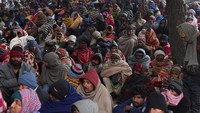 Puluhan orang berkumpul di kawasan Sungai Yamuna, New Delhi, sambil mengenakan pakaian hangat.