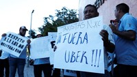 Seorang pengemudi taksi memegang tanda bertuliskan: Uber Out selama protes terhadap regulasi aplikasi taksi seperti Uber di Cancun, Meksiko 11 Januari 2023.