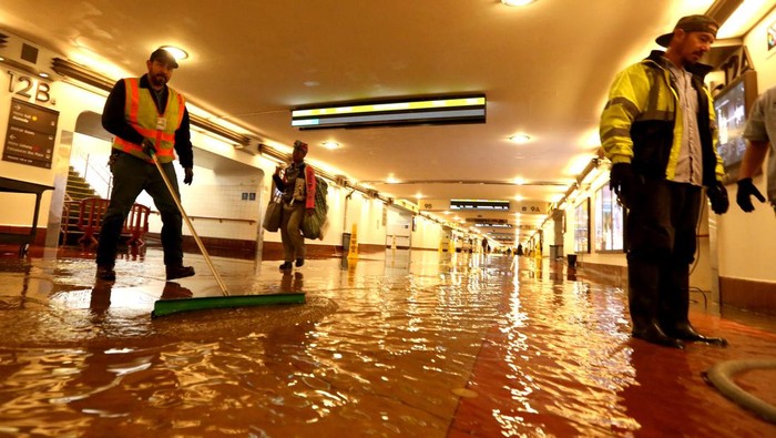 LOS ANGELES, CA -  JANUARY 10, 2023 - - Metro workers help clear a flooded section of the pedestrian walkway leading to train platforms on the main level of Union Station in downtown Los Angeles on January 10, 2023. Many commuters were shuttled over the flooded section caused by the latest rain storm in Southern California. (Genaro Molina / Los Angeles Times via Getty Images)