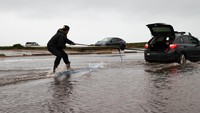 Seorang pria bermain selancar di jalanan yang terendam banjir di Fort Funston, San Francisco, California, Amerika Serikat, Rabu (11/1/2023).