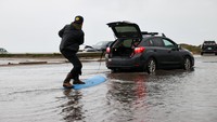 Banjir yang belum menyusut dimanfaatkan sejumlah warga untuk bermain selancar.    
