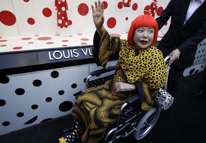 Japanese artist Yayoi Kusama waves in front of the windows of Vuittons flagship store for the unveiling of a new collaborative collection by Vuitton and creative designer Marc Jacobs in New York, Tuesday, July 10, 2012.  (AP Photo/Kathy Willens)