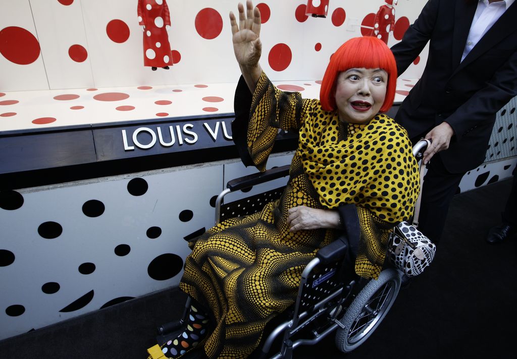 Japanese artist Yayoi Kusama waves in front of the windows of Vuitton's flagship store for the unveiling of a new collaborative collection by Vuitton and creative designer Marc Jacobs in New York, Tuesday, July 10, 2012.  (AP Photo/Kathy Willens)