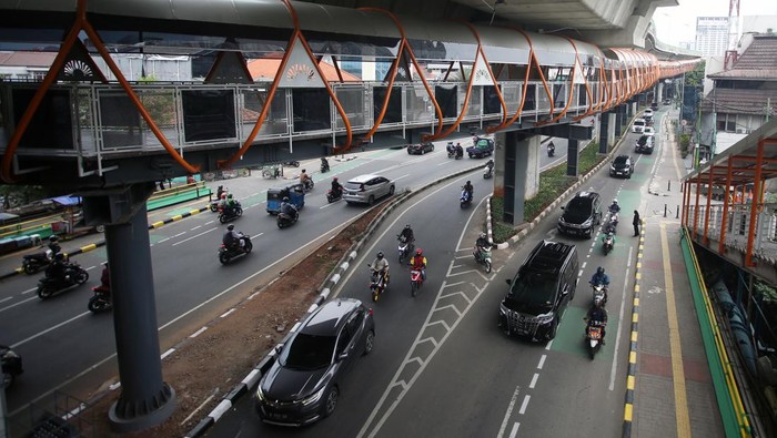 Commuter Line melintas di bawah jembatan penyeberangan orang (JPO) atau 