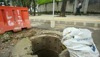 Tampak road barrier hingga karung pasir diletakkan di sekitar lubang untuk menghindari jatuhnya korban.