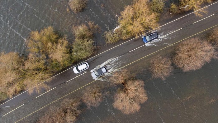 Cars make their way along the flooded A1101 in Welney in Norfolk, where the River Delph and New Bedford River have flooded the surrounding area. Picture date: Thursday January 5, 2023. (Photo by Joe Giddens/PA Images via Getty Images)