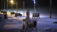 Seekor anjing duduk di atas tempat berlindungnya di halaman anjing di Bolterdalen, Norwegia. Halaman tersebut terletak setengah lusin mil dari desa utama di Svalbard, sebuah kepulauan Norwegia yang begitu dekat dengan Kutub Utara sehingga musim dingin diselimuti kegelapan tanpa gangguan. AP/Daniel Cole  