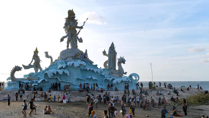 Wisatawan menikmati pemandangan matahari terbenam dari dekat Patung Triratna Amreta Bhuwana di kawasan wisata Pantai Jerman, Kuta, Badung, Bali, Kamis (12/1/2023). Patung Triratna Amreta Bhuwana yang baru selesai pembangunannya sebagai bagian dari proyek penataan Pantai Seminyak, Legian, Kuta (Samigita) itu dibangun sebagai ikon pariwisata baru untuk menarik kunjungan wisatawan ke Pantai Jerman. ANTARA FOTO/Fikri Yusuf/aww.