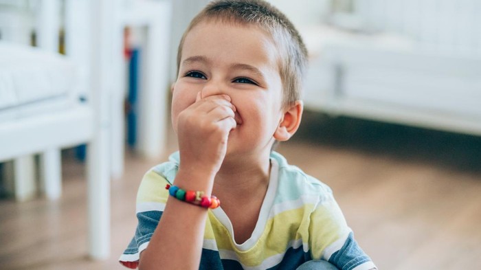Portrait of a cute little boy holding his nose for sign of bad smell.
