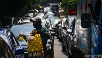 Salah seorang pedagang asongan memanfaatkan macet dengan menjajakan dagangannya. 