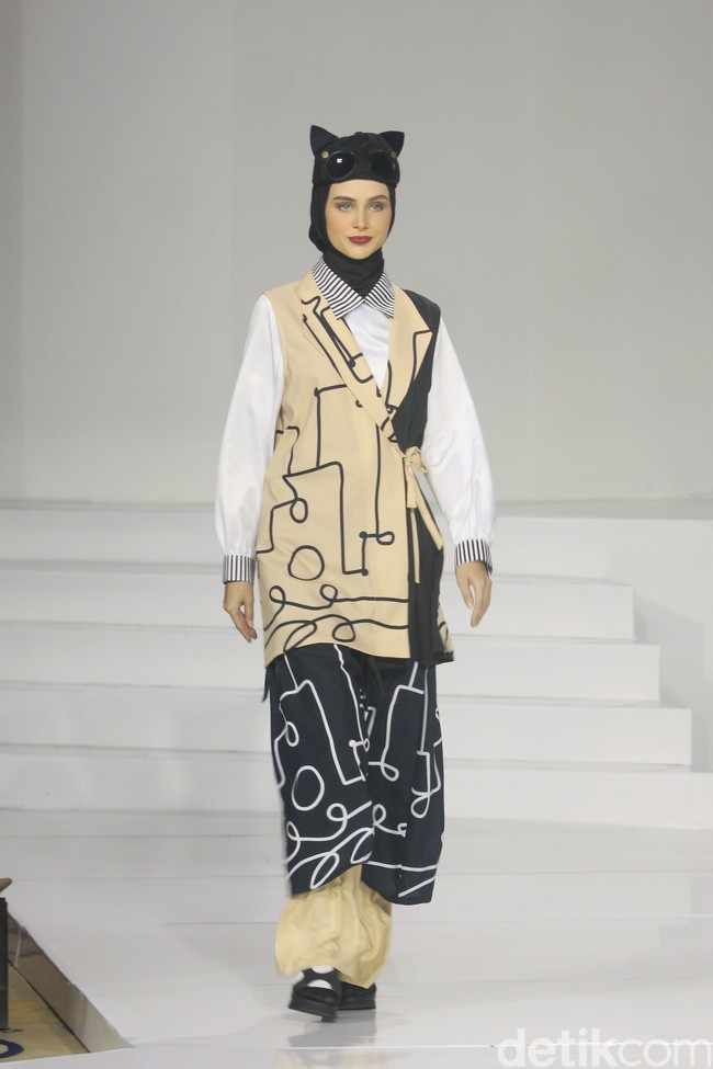 Koleksi busana Hannie Hananto dengan gambar perempuan yang artsy. Hannie merilis busana muslim yang didominasi warna marun, krem dan hitam di Jakarta Fashion Trend 2023. . Foto: Mohammad Abduh/Wolipop.