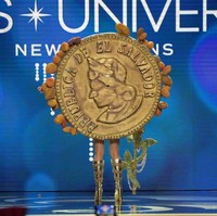 Aksesori Bitcoin raksasa berwarna emas disematkan di bagian punggung Miss Universe El Salvador 2022 Alejandra Guajardo. Ada juga detail biji cokelat di busana yang dipakai Alejandra. Bitcoin yang ditempelkan di busana Alejandra itu merupakan buatan seniman Francisco Guerrero. Foto: Getty Images